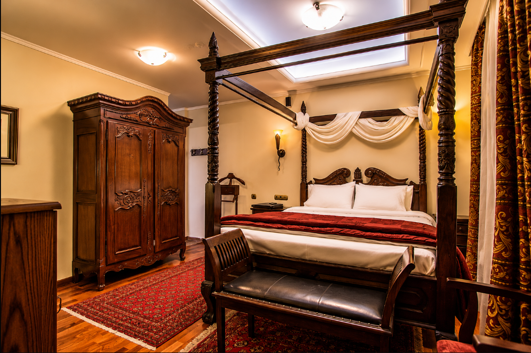 A guest room at Enterne with dark timber ceiling beams, stone walls and warm lamp light
